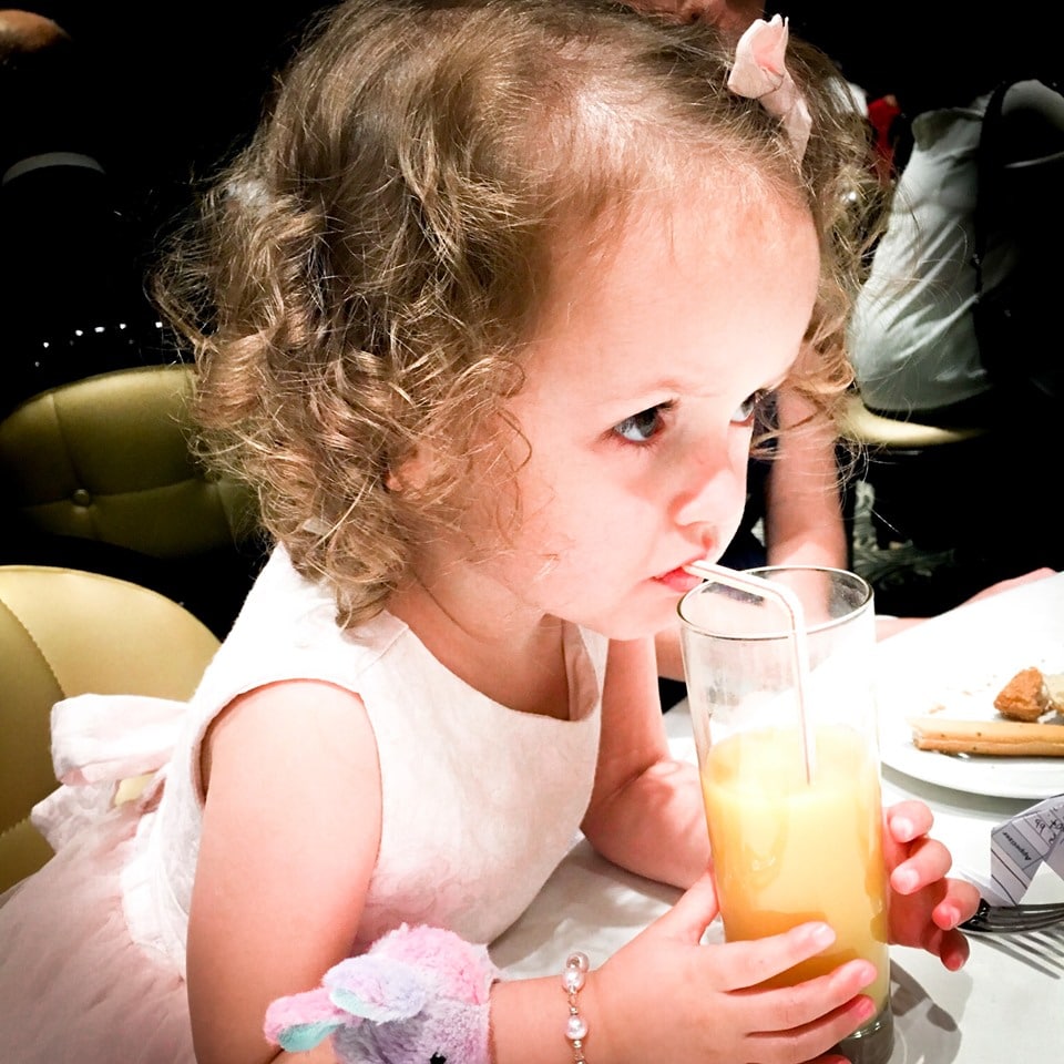 Toddler drinking juice during dinner at a cruise ship dining room