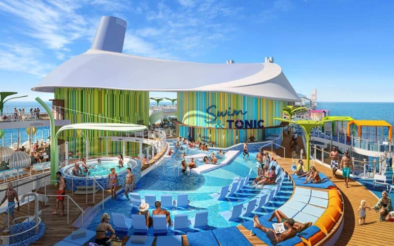 Busy pool deck scene at 'Chill Island' on Royal Caribbean's 'Star of the Seas,' featuring a large, vibrant swimming area. Guests relax in blue sun loungers and enjoy the water in circular pools, while others gather under a large white canopy. The area is accented with colorful, vertical stripes, creating a lively, vacation-ready atmosphere.