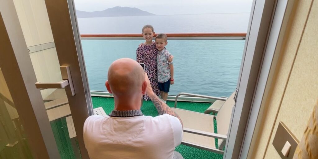 Dad taking photo of children on cruise ship balcony