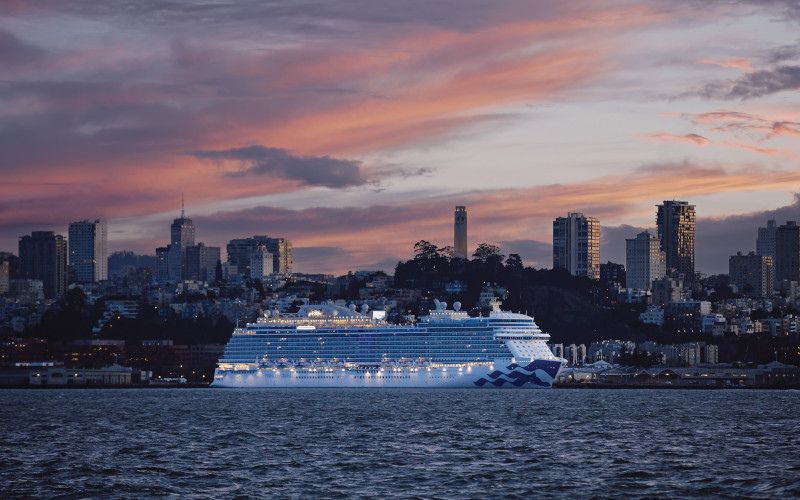 Discovery Princess cruising the ocean with a magestic cityscape behind