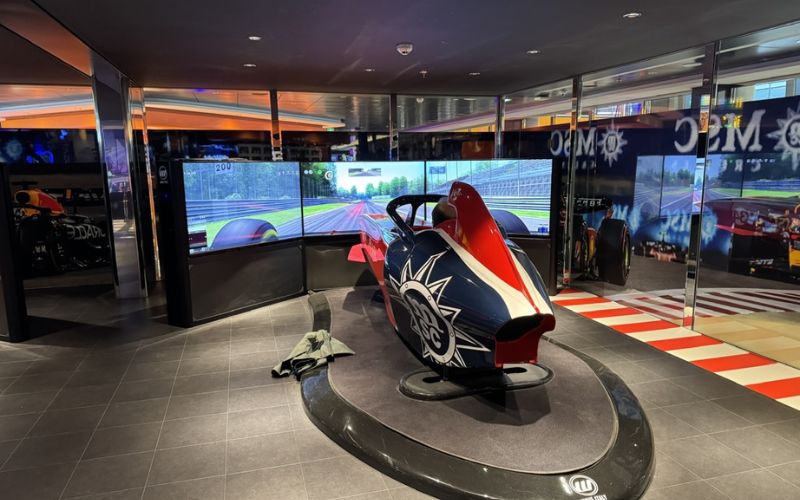 A formula 1 simulator in front of a 3-monitor gaming setup available for MSC FUN PASS subscribers