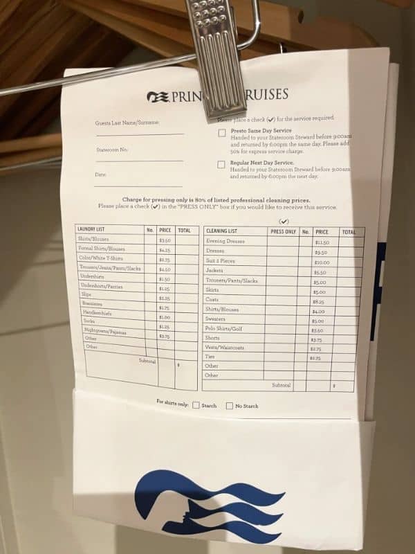 A laundry service order form on a Princess cruise ship clipped to a hanger. The form lists various items for laundry and cleaning services, including shirts, blouses, pants, jackets, dresses, and other garments, along with their respective prices. Options for pressing and starch preferences are also available, and the form features the Princess Cruises logo at the bottom.