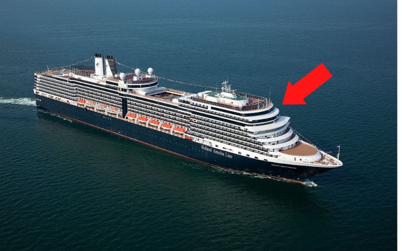 Holland America Line cruise ship sailing on the ocean with red arrow pointing to the top decks at the bow of the ship