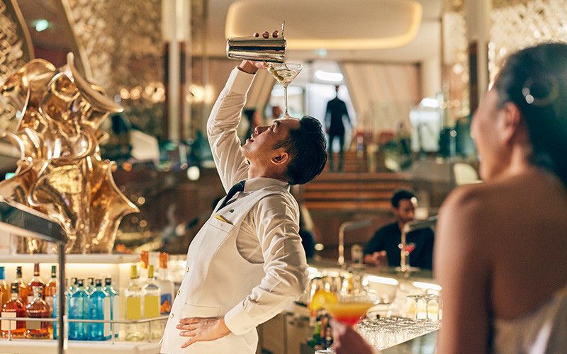 A cool bartender showing off his skills, serving customers onboard their drinks