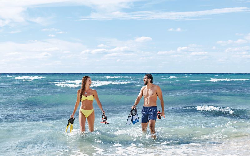 couple at the beach holding a snorkeling gears