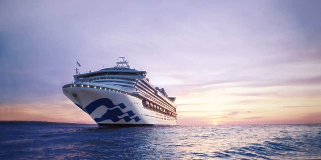 Sapphire Princess sailing on the water with a sunset behind the ship.