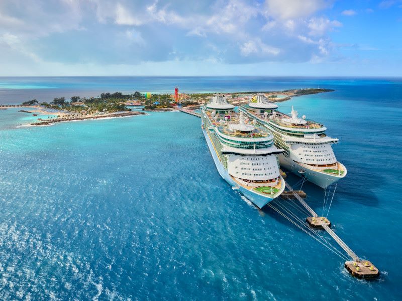 Royal Caribbean cruise ships docked at Perfect Day at CocoCay, Royal Caribbean's private island, where guests can enjoy exclusive beach activities, with the vibrant colors of the aqua park and island attractions highlighting the ultimate vacation experience.