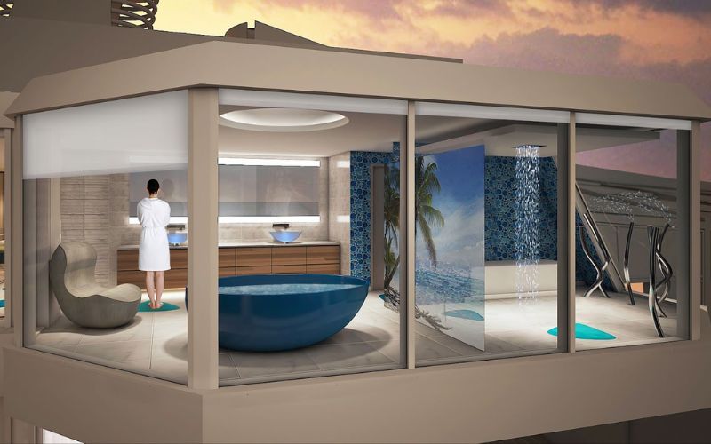 An artistic rendering of the Ultimate Family Suite on Royal Caribbean's Spectrum of the Seas, showcasing a spacious, modern bathroom with a large blue round bathtub, floor-to-ceiling windows with ocean views, and a person in a white robe looking out.
