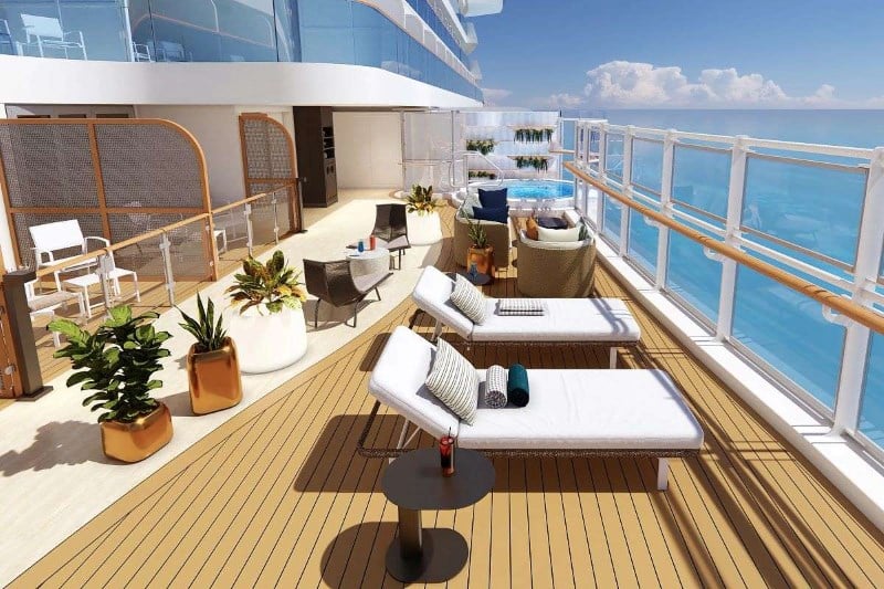 This image showcases the Sun Princess cabana deck. It features two white sun loungers with striped pillows and rolled towels, a small round table with a drink, potted plants, comfortable seating arrangements, and a hot tub. The clear blue ocean and sky provide a serene backdrop.