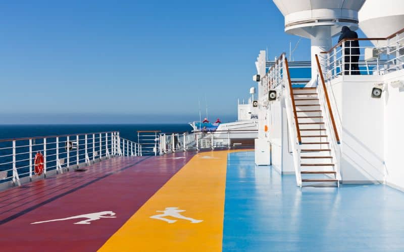 Color-coded running and walking tracks in the recreation area on a cruise ship's deck, with clear symbols indicating lanes against the backdrop of the vast blue ocean and clear skies, promoting fitness and leisure at sea.