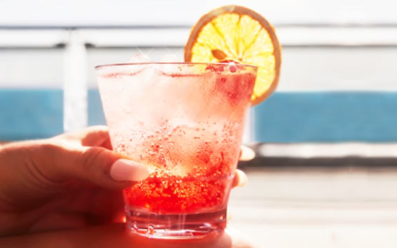 A woman's manicured hand holding a refreshing brightly coloured drink