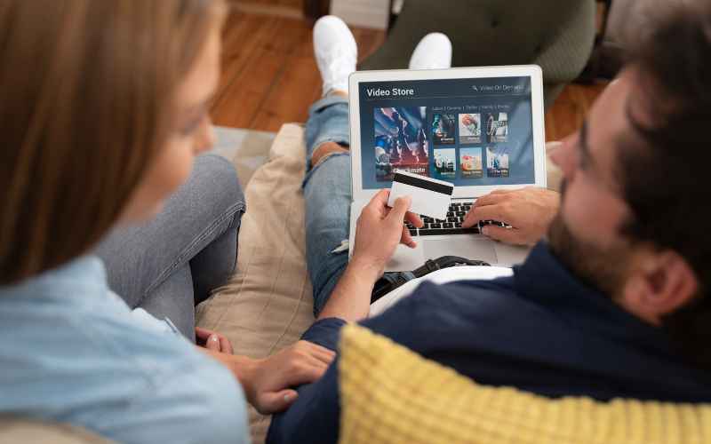 Woman and a man looking at their online shopping subscriptions on a laptop.