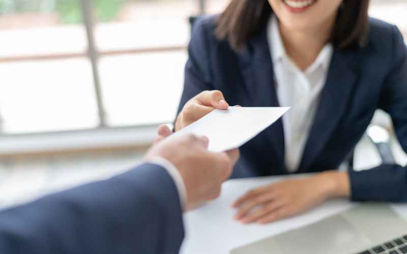 A woman being handed a cheque from her boss at work.