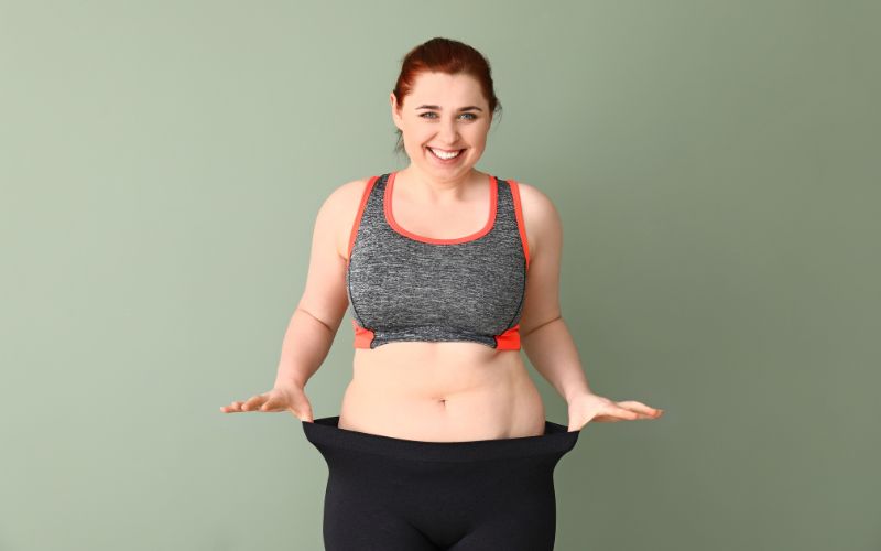 A smiling woman showing how elastic her leggings are