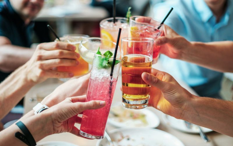 A selection of colourful alcohol-free drinks, including fruit juices and mocktails, arranged on a table. The beverages are garnished with fresh fruit and ice, creating a refreshing and inviting display