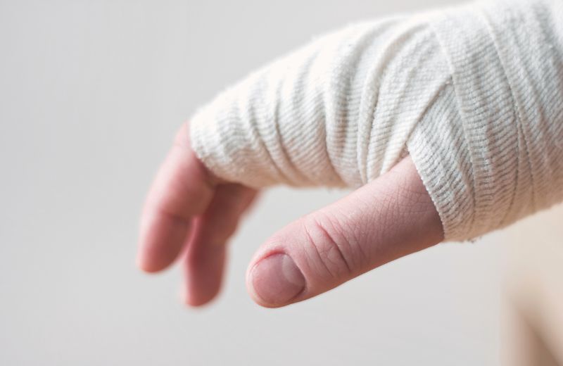 Close-up of a person's hand with fingers extended, wrapped in a clean white bandage, indicating a recent injury or medical treatment.