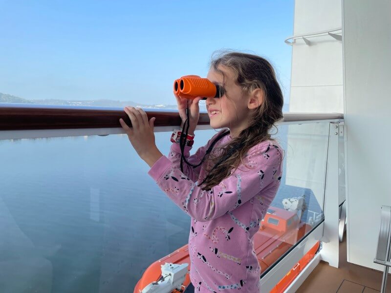 Child on balcony looking through binoculars at the view