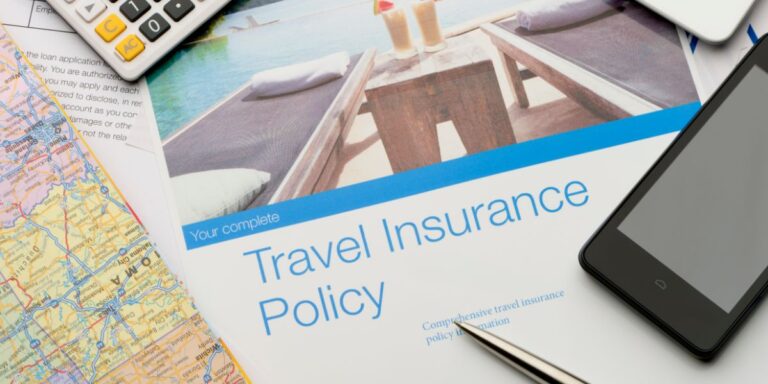A brochure for 'Your complete Travel Insurance Policy' on a table with travel essentials, including a map, calculator, and smartphone, emphasizing the importance of comprehensive travel insurance for cruises.