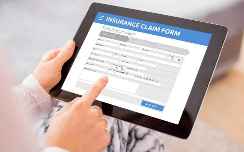 person's hands holding an ipad showing an Insurance Claim form