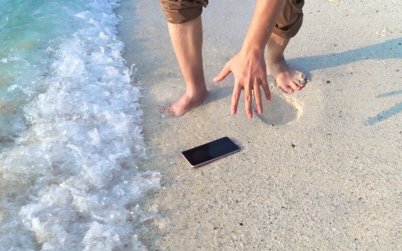 Man dropped phone on sand near the ocean