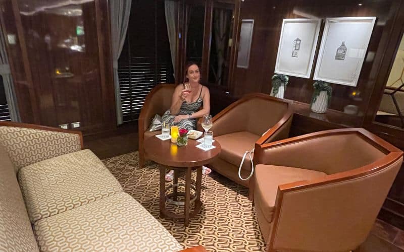 A woman enjoys a relaxing moment with a beverage in an elegantly furnished lounge area, suggesting a serene and comfortable environment.