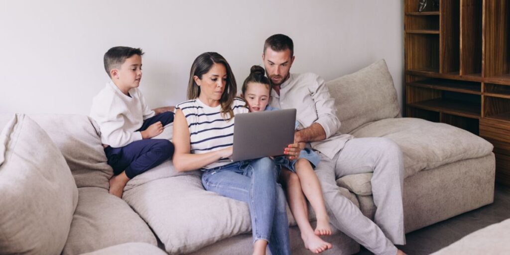 Family sat around laptop looking at cruise travel insurance
