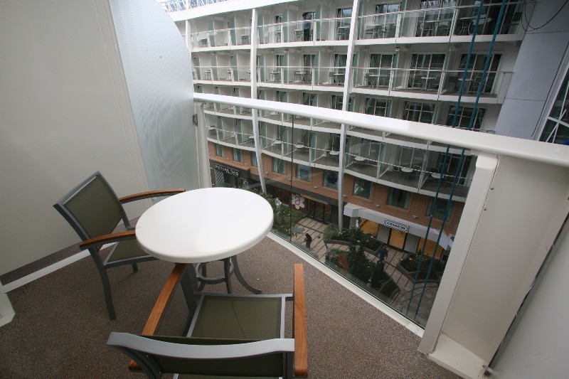 View from an interior balcony stateroom on Oasis of the Seas, featuring a cozy table and chairs setup overlooking the ship's open-air central park.