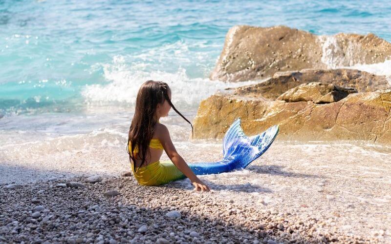 Child dressed as a mermaid on a beach