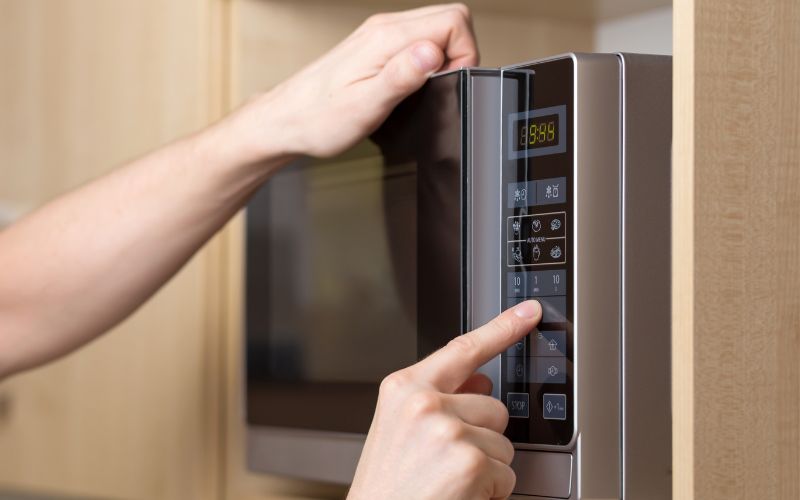 A person trying to use a malfunctioning microwave on a cruise cabin