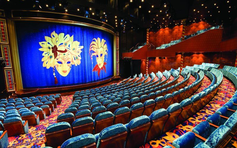 An empty theatre inside one of NCL's cruise ships with a huge blue curtain covering the main stage