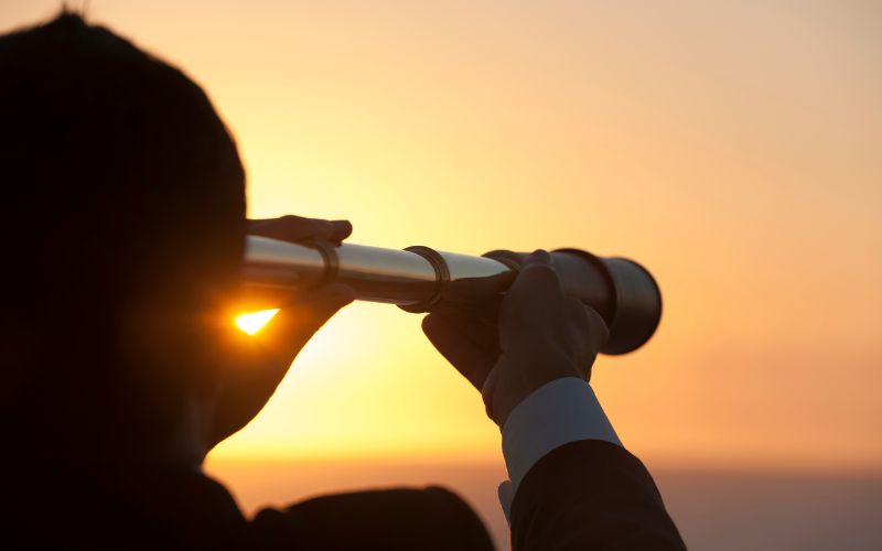 A man gazes through a telescope, enjoying a stunning sunset during his trip.